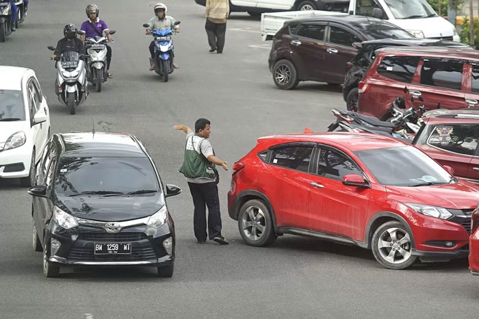 Petugas parkir mengatur kendaraan parkir, di Jalan Jendral Sudirman, Pekanbaru. Selasa (28/5/2024). (DEFIZAL / Riau Pos)