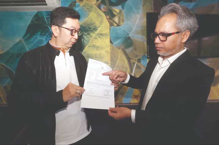 UPAYA HUKUM: Martin Suryana (kiri) dan Subuh Susilo, pengacara LS, menunjukkan surat laporan kepolisian terkait dugaan penipuan investasi.