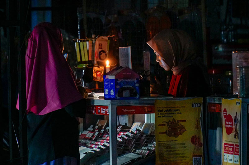 Konter pulsa menggunakan lilin sebagai penerangan di Jalan Cipta Karya, Rabu (5/6/2024). Pemadaman bergilir oleh PLN dikarenakan adanya pemeliharaan jaringan berdampak besar pada warga di Riau.