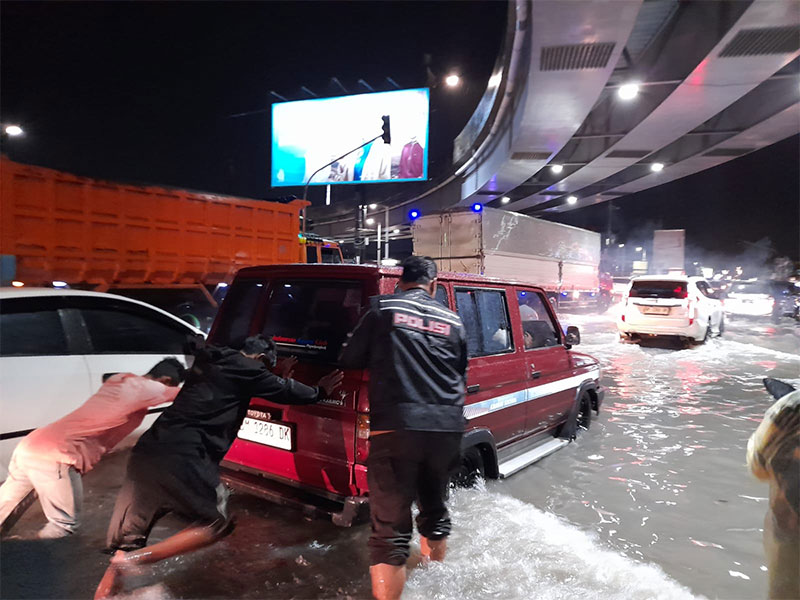 Polisi mendorong kendaraan mogok di Jalan HR Soebrantas pada Jumat (21/6/2024),