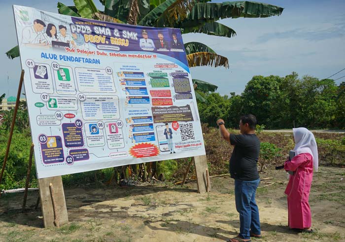 Warga melihat pengumuman persyaratan pendaftaran Penerimaan Peserta Didik Baru (PPDB) 2024 di SMAN 19, Jalan Garuda, Kecamatan Binawidya, Kelurahan Tobek Godang.