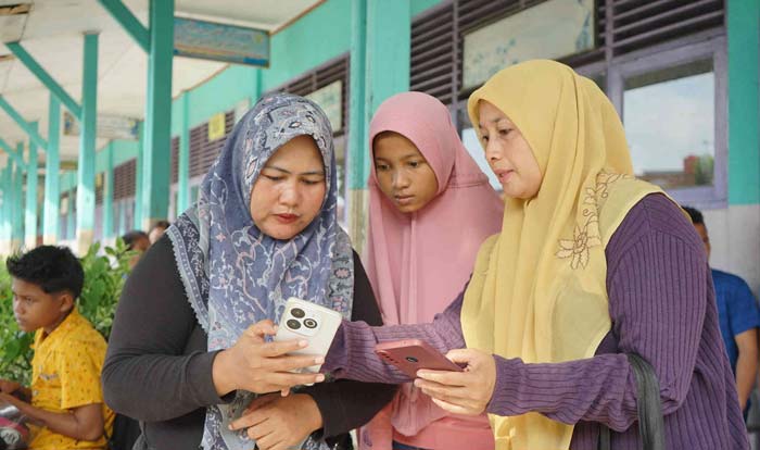 Orang tua calon peserta didik melihat ponsel saling berbagi informasi terkait Penerimaan Peserta Didik Baru di SMPN 25 Pekanbaru Jalan Kartama, Pekanbaru, Rabu (26/6/2024).