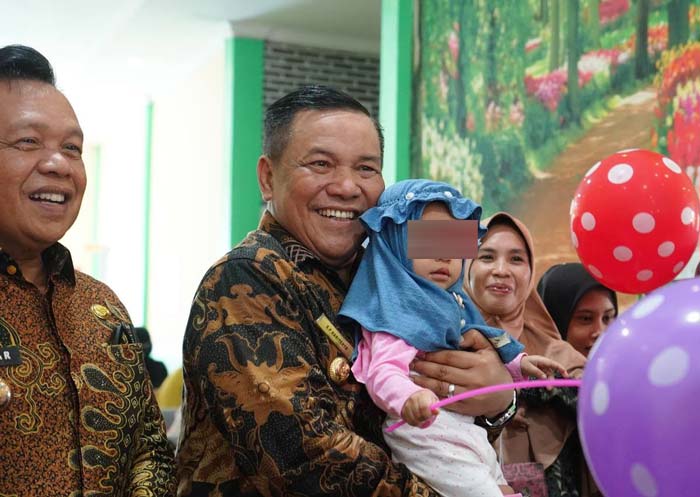 Penjabat Gubernur Riau SF Hariyanto menggendong balita saat pembagian susu untuk pencegahan stunting di Kabupaten Kepulauan Meranti, Kamis (27/6/2024).