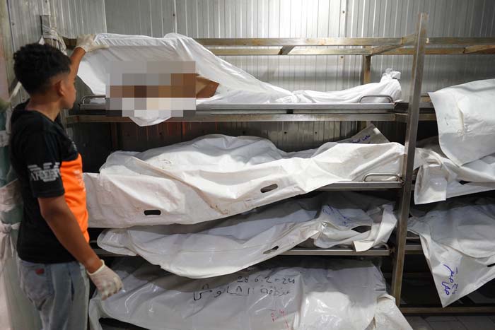 Seorang pemuda Palestina yang bekerja di kamar mayat membuka kain kafan salah seorang korban yang terbunuh akibat serangan Israel di Rumah Sakit Nasser, Khan Yunis, Gaza, Jumat (5/7/2024).