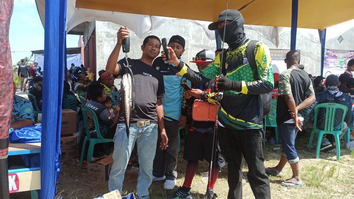 Salah seorang peserta lomba mancing Joko (kanan) saat tengah menyaksikan ikan Gabus yang berhasil di angkatnya ditimbang panitia, Ahad (7/7/2024).