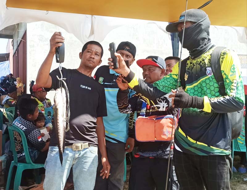 Salah seorang peserta lomba mancing Joko (kanan) menyaksikan ikan gabus yang sedang ditimbang panitia saat mengikuti lomba mancing  Family Gathering Angler Riau.