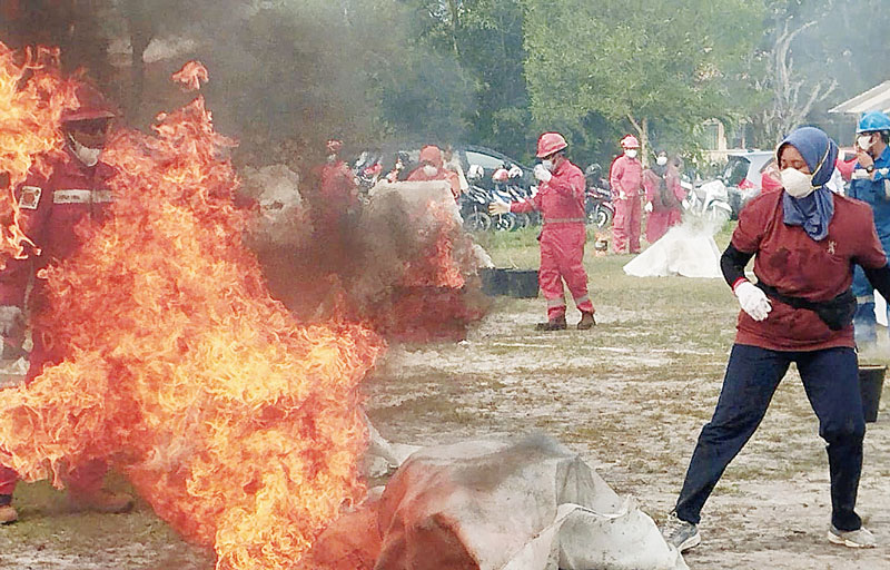 Salah seorang wanita mengikuti latihan peragaan untuk menjinakkan dan memadamkan kobaran api yang diadakan oleh PT Pertamina Kilang Internasional (KPI) Unit Dumai di lapangan sepakbola SMP YKPP, Kompl
