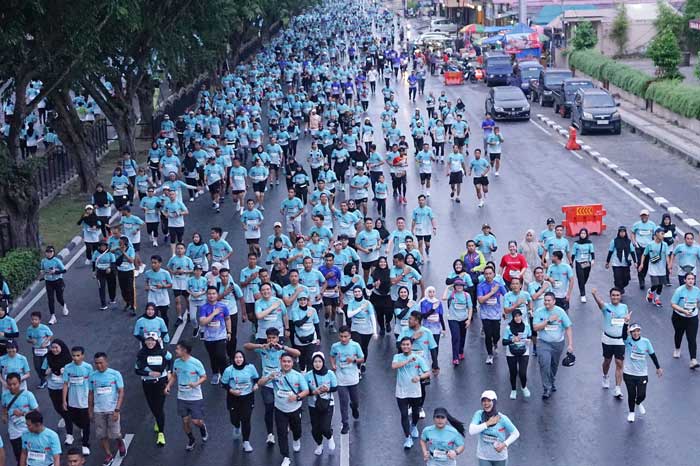 Kapolda Riau Irjen Pol Mohammad Iqbal dan Istri Nindya M Iqbal berfoto bersama ribuan peserta Riau Bhayangkara Run 2024 yang melintas di Jalan Sudirman, Pekanbaru, Ahad (14/7/2024).