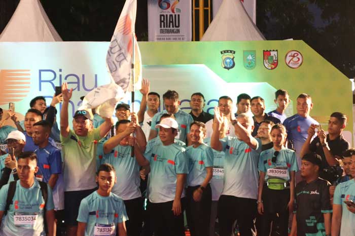 Ketua DPRD Riau Yulisman (topi putih) mengangkat bendera Riau Bhayangkara Run bersama Pj Gubernur Riau SF Hariyanto tanda dimulainya balapan, Ahad (14/7/2024).