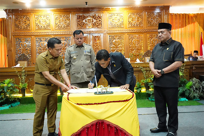 Wakil Ketua I DRPD Kuansing, Drs H Darmizar menandatangani berita acara pengesahan dua Perda yang diusulkan  Pemkab dalam paripurna, Senin (22/7/2024).