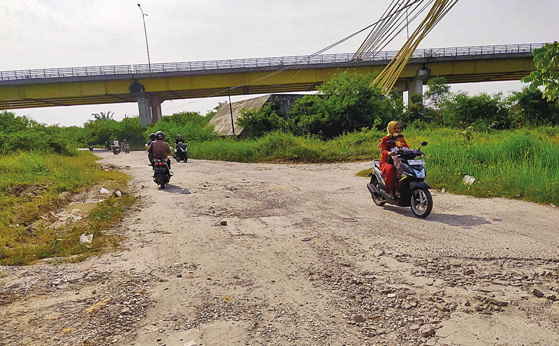 Pengendara melintas di Jalan Pesisir, Kecamatan Rumbai yang mengalami kerusakan cukup parah, Senin (22/7/2024). Kerusakan ini sudah berlangsung lama, namun belum ada upaya perbaikan dari