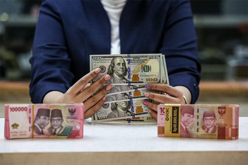 Karyawan menunjukan uang dolar Amerika Serikat (AS) dan Rupiah di salah satu gerai penukaran mata uang asing di Jakarta, Selasa (18/6/2024).