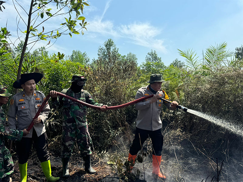 Kapolres Rokan Hilir AKBP Isa Imam Syahroni (kanan) saat memadamkan salah satu titip api di Kepenghuluan Rantau Bais, Kecamatan Tanah Putih, Kabupaten Rohil, Rabu (24/7/2024).