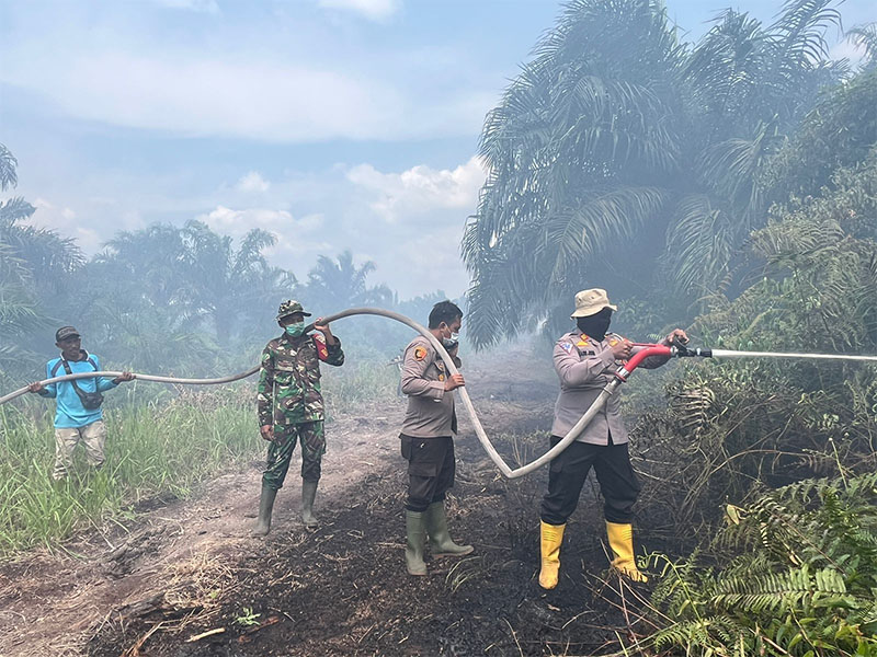 Petugas dari TNI-Polri di Kabupaten Rokan Hilir saat melakukan pemadaman lahan yang terbakar, baru-baru ini.