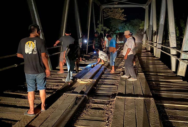 Warga bergotong royong melakukan perbaikan akibat lantai jembatan sudah banyak yang bolong, Jumat (26/7/2024) kemarin.