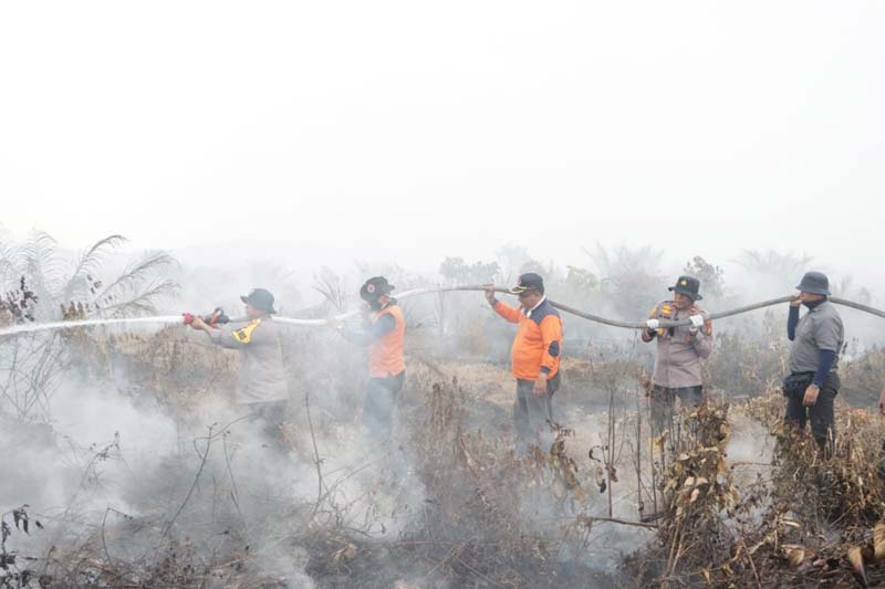 Kapolres Siak AKBP Asep Sujarwadi melakukan pemadaman api di Kampung Buantan Besar, Kecamatan Siak, Selasa (30/7/2024).