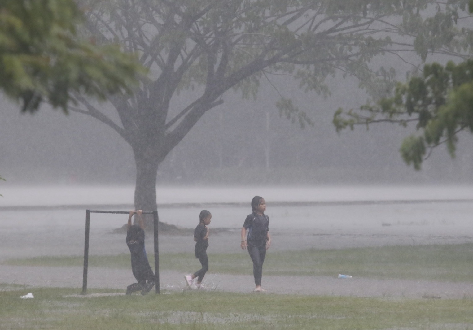 Anak-anak  bermain air ketika hujan mengguyur kota Pekanbaru pada Rabu (31/7) pagi di kawasan Bandar Seni Raja Ali Haji.