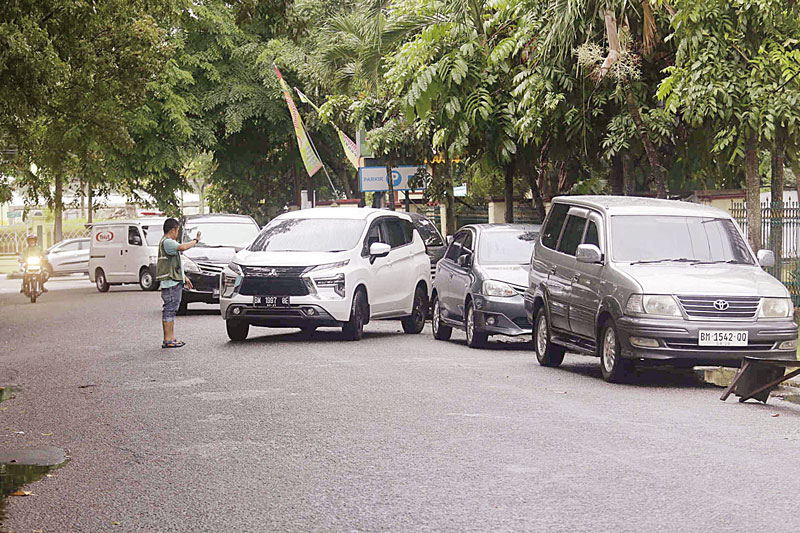 Jukir mengatur parkir mobil di Jalan Mustika samping RSUD Arifin Achmad Pekanbaru, Rabu (31/7/2024). Oknum jukir diduga meminta tarif Rp10 ribu kepada pengendara roda empat yang parkir.