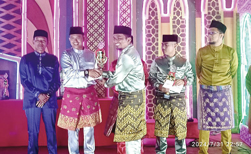 Camat Pinggir Zamarico Dakanahay menyerahkan trofi juara umum kepada Kades Muara Basung, pada malam penutupan MTQ XX Tingkat Kecamatan Pinggir, Rabu (31/7/2024) malam.