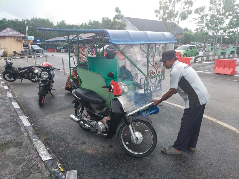 Para tukang becak motor menunggu penumpang sambil membenahi becaknya di Pelabuhan Ro-Ro Air Putih Bengkalis, Jumat (2/8/2024).