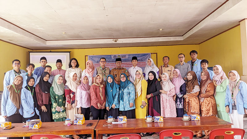 FOTO BERSAMA: Pj Kepala Desa Teluk Pambang Sariyono (baju dinas) didampingi Ketua Tim Dr Sumarto SPi MSi (pakai rompi) foto bersama para tim dosen pengabdian dan mahasiswa kukerta Universitas Riau di
