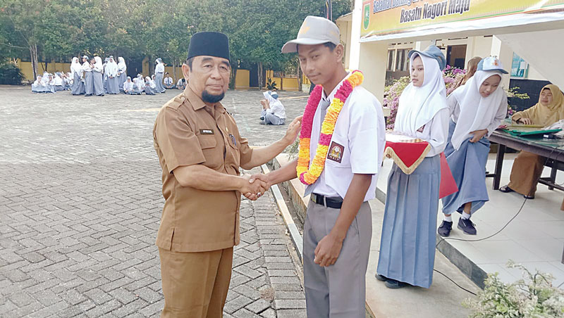 UCAPKAN SELAMAT: Kepala SMAN 1 Sentajo Raya Drs Afrizal mengucapkan selamat pada Rizki Pahlefi,  juara tenis lapangan Merah Putih Cup Kabupaten Kuansing 2024, Senin (12/8/2024).