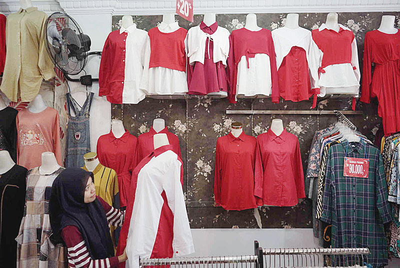 Pedagang menyusun baju bernuansa merah putih di salah satu toko penjual baju di Jalan Delima, Kecamatan Binawidya,  Pekanbaru, Ahad (11/8/2024).