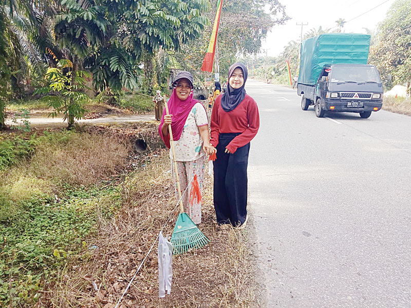 MENGHIAS: Seorang ibu dan remaja putri di Bungaraya menghiasi tepi jalan sambil bersih-bersih, Senin (12/8/2024).