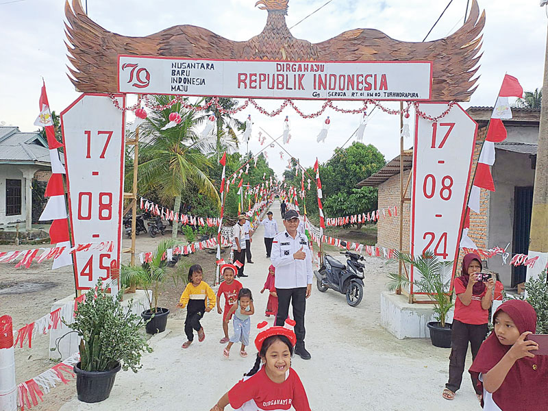 SAMBUT HUT RI: Warga Kampung Tuah Indrapura, Kecamatan Bungaraya, Kabupaten Siak menghiasi jalan lingkungan dengan umbul-umbul bendera Merah Putih dalam menyambut HUT ke-79 RI, Rabu (14/8/2024).