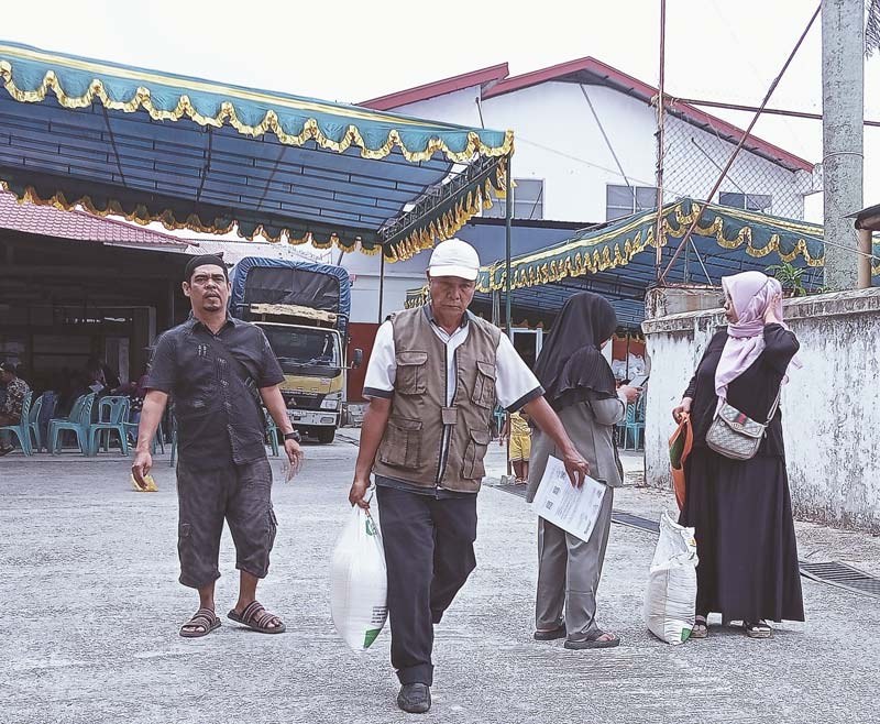 Warga membawa beras bantuan dari pemerintah yang diambil di Kantor Pos Pekanbaru, Rabu (14/8/2024).