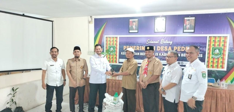 SERAHKAN BANTUAN: Kadisbun Bengkalis Muhammad Azmir menye&shy;rahkan bantuan bibit dan saprodi tanaman kopi kepada petani di Desa Pedekik, Kecamatan Bengkalis, Rabu (14/8/2024).