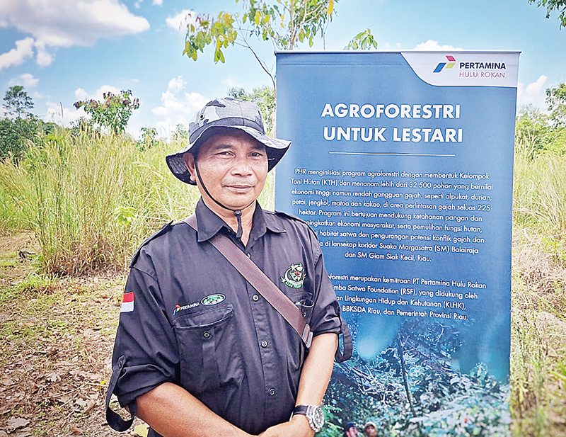 Sekretaris KTH Alam Pusaka Jaya, Suparto berfoto di depan standing banner Pertamina, baru-baru ini.