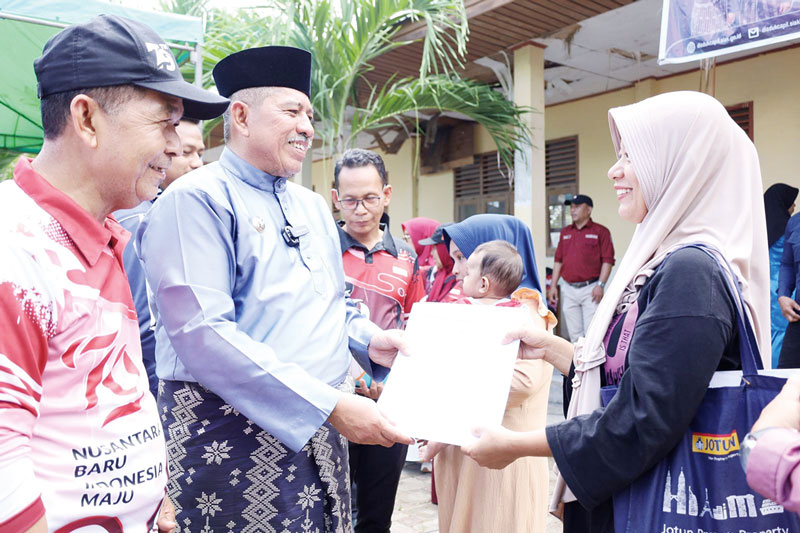 Bupati Siak Alfedri didampingi Kadisdukcapil Hasmizal memberikan berkas pelayanan kepada warga saat Bujang Kampung di Kayu Ara, Kecamatan Sungai Apit, Kabupaten Siak, Jumat (16/8/2024).