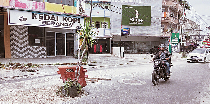 Pengendara melintas di lokasi bekas lubang SPALD-T di Jalan KH Ahmad Dahlan, yang ditanami pohon pandan laut, Kamis (22/8/2024).