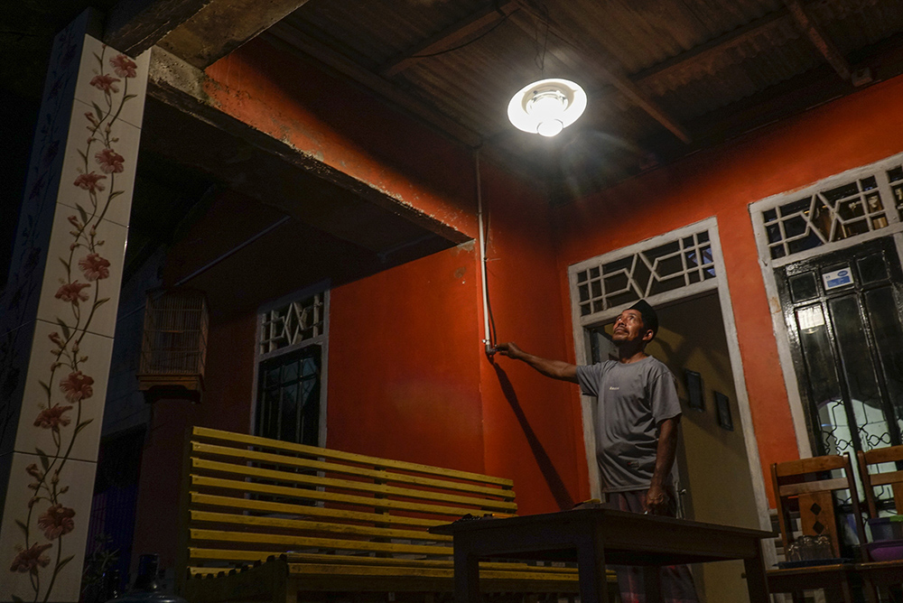 LAMPU PENERANGAN: Sudarman,  membuka aliran gas untuk menyalakan lampu petromak menggunakan energi biogas yang barasal dari peternakan sapi sebagai sumber penerangan rumah nya di Desa Muktisari,Tapung, Kampar, Riau, Senin (12/8/2024) Malam.