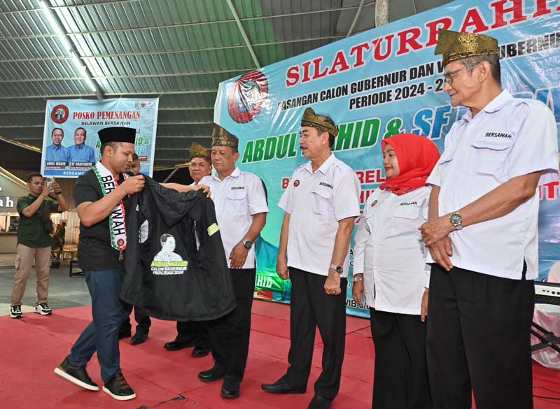 Bacalon Gubri Abdul Wahid memasangkan rompi kepada relawan Bersawah di Riau Garden, Pekanbaru, Ahad (1/9/2024).