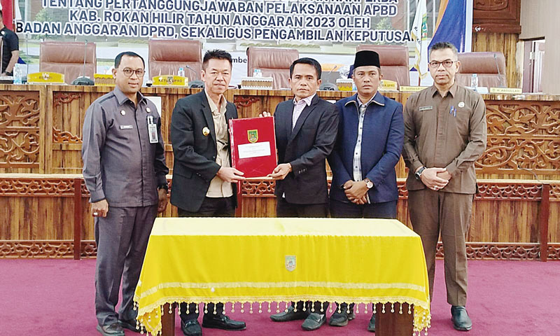 Ketua DPRD Rohil Maston didampingi Wakil Ketua Hamzah, Kabag Persidangan dan Perundangan Julianda menyerahkan SK penetapan Ranperda Pertanggungjawaban Pelaksanaan (PP).