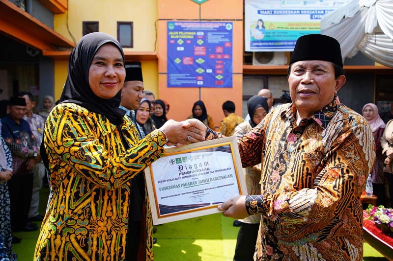 Bupati Rohul H Sukiman menyerahkan piagam penghargaan kepada Kepala Puskesmas Pagaran Tapah Darussalam Hj Kholida Hosni, SST MKM saat launching ILP Puskesmas, Pustu dan Posyandu.