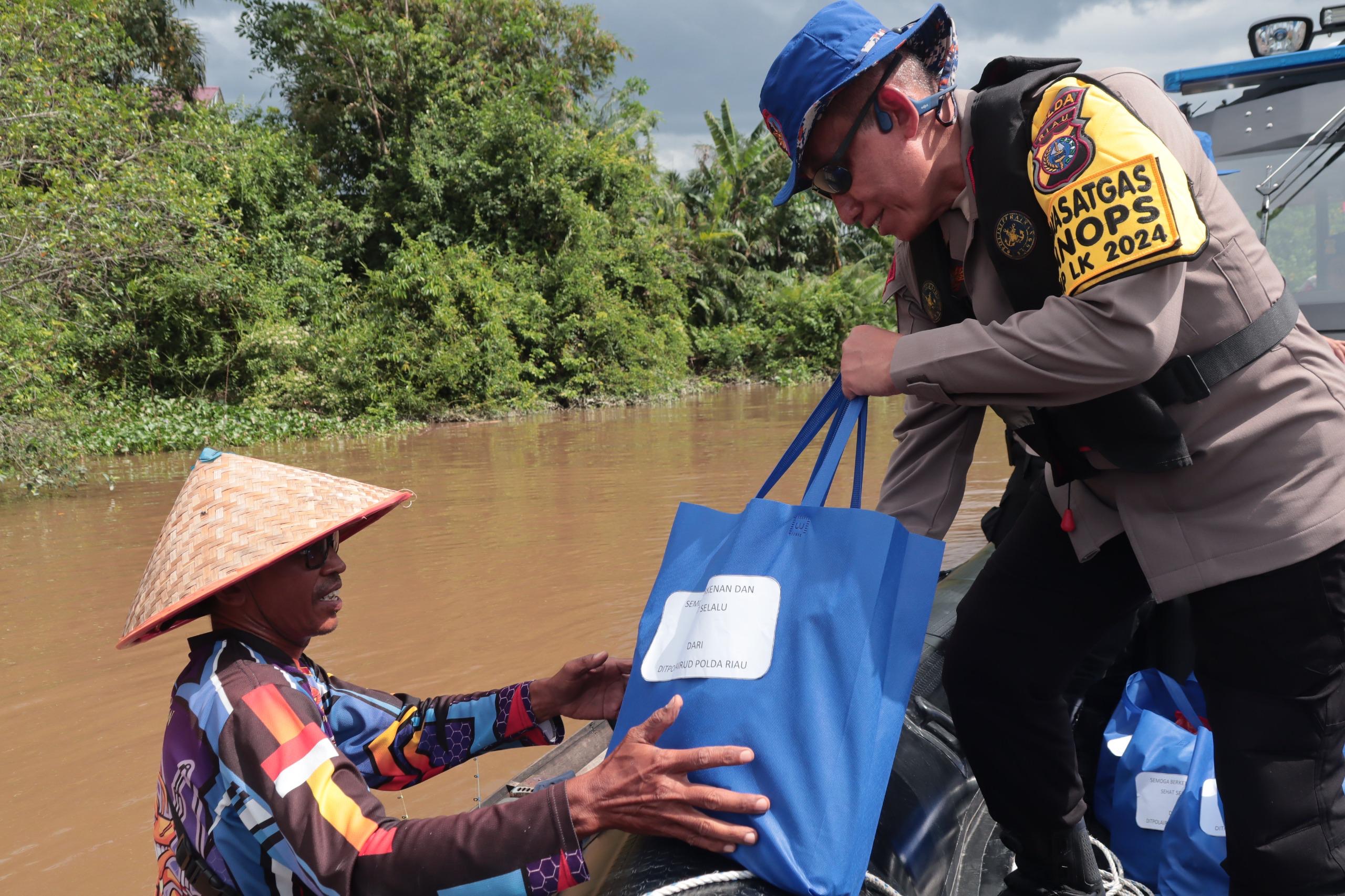 Dirpolairud Polda Riau Kombes Pol Wahyu Prihatmaka membagikan bantuan sembako kepada nelayan sambil mengajak untuk mewujudkan Pilkada damai, Jumat (20/9/2024).