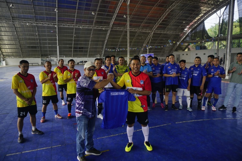 Pimpinan Cabang Bank BJB Pekanbaru Yusriyadi menerima baju dari Sekretaris PWI Riau Doni Dwi Putra sebelum laga ekshibisi digelar di Aero Sport Futsal Pekanbaru, Sabtu (21/9/2024).