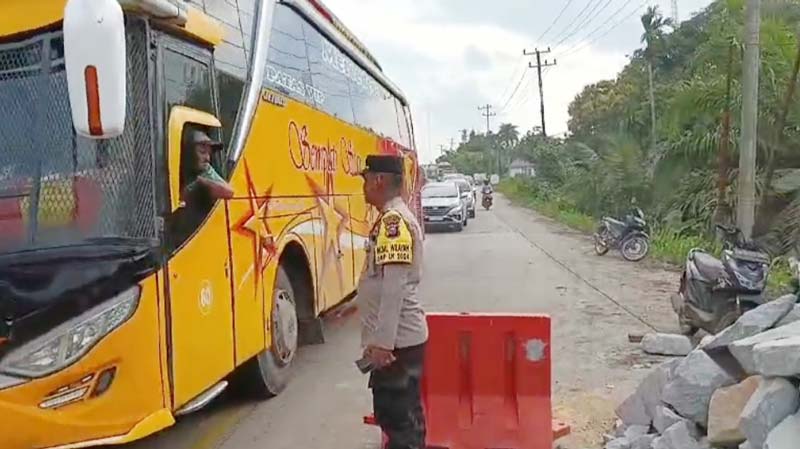Kapolsek Rengat Barat AKP Buha Siahaan SH mengatur arus lalu lintas kendaraan yang melintas di Jalan Lintas Timur Km 192 Desa Sungai Dawu yang mengalami abrasi, Sabtu (21/9/2024).