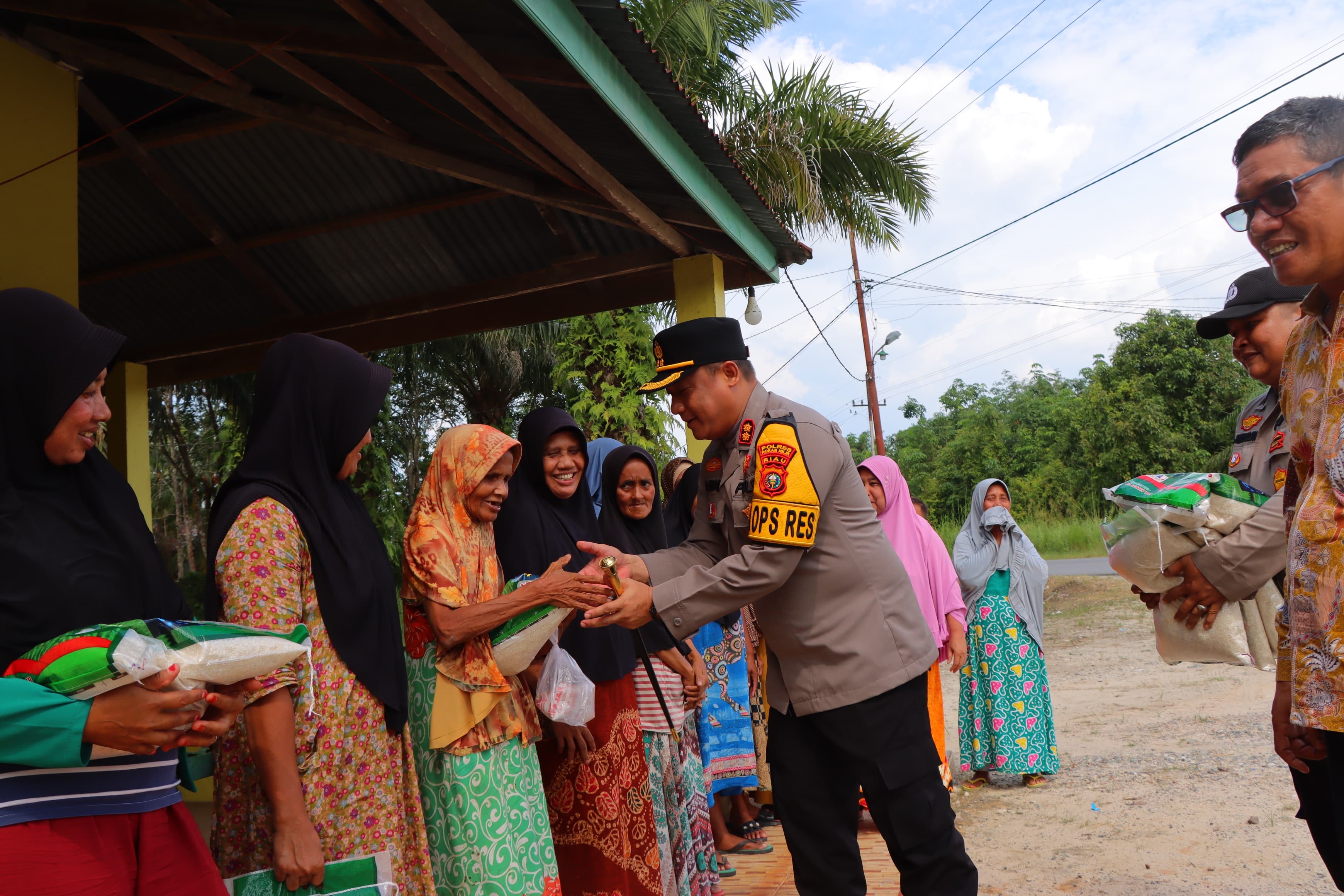 Kapolres Rohil AKBP Isa Imam Syahroni SIK MH menyerahkan bantuan sosial untuk warga saat gelar cooling system, disela silaturahmi dengan tokoh masyarakat di Kepenghuluan Sintong Kecamatan Tanah Putih.