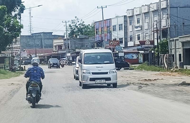 Pengendara mini bus mengurangi laju kendaraannya ketika melewati ruas Jalan Rengat Pematang Reba yang mengalami rusak berat di Kelurahan Pematang Reba, Rabu (2/10/2024).