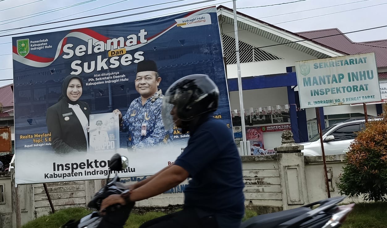 Salah seorang warga melintas di baliho Bupati Inhu Rezita Meylani Yopi SE bersama Kepala Inspektorat Inhu, Boyke Elman Sitinjak SE MSi, Kamis (3/10/2024.