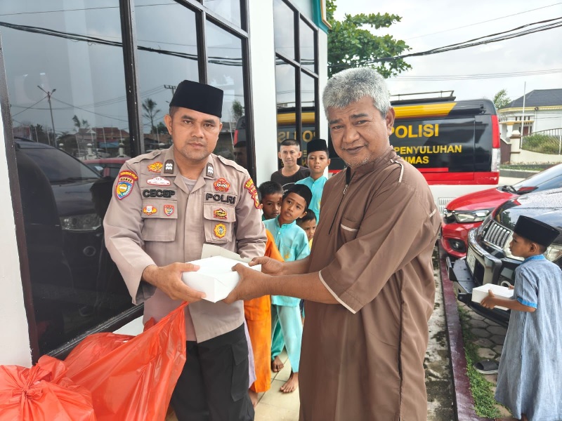 Personel Satbinmas Polres Pelalawan saat membagikan nasi kotak kepada masyarakat, Jumat (4/10/2024).