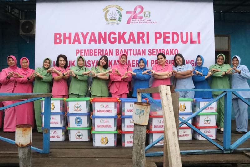 Ketua Bhayangkari Dumai Widia Dhovan bersama para ketua organisasi wanita lainnya foto bersama sambil bergandengan tangan saat menyalurkan bansos