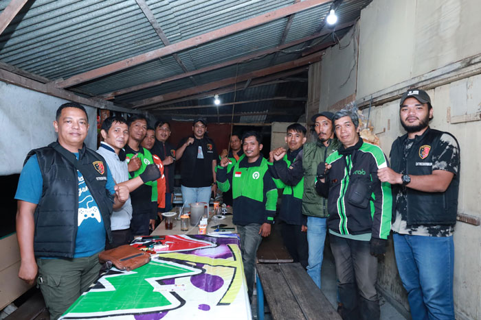 Petugas dari Ditreskrimum Polda Riau berfoto bersama ojek online yang sedang menunggu orderan di Jalan Kuantan, Pekanbaru, Sabtu (5/10/2024) malam.