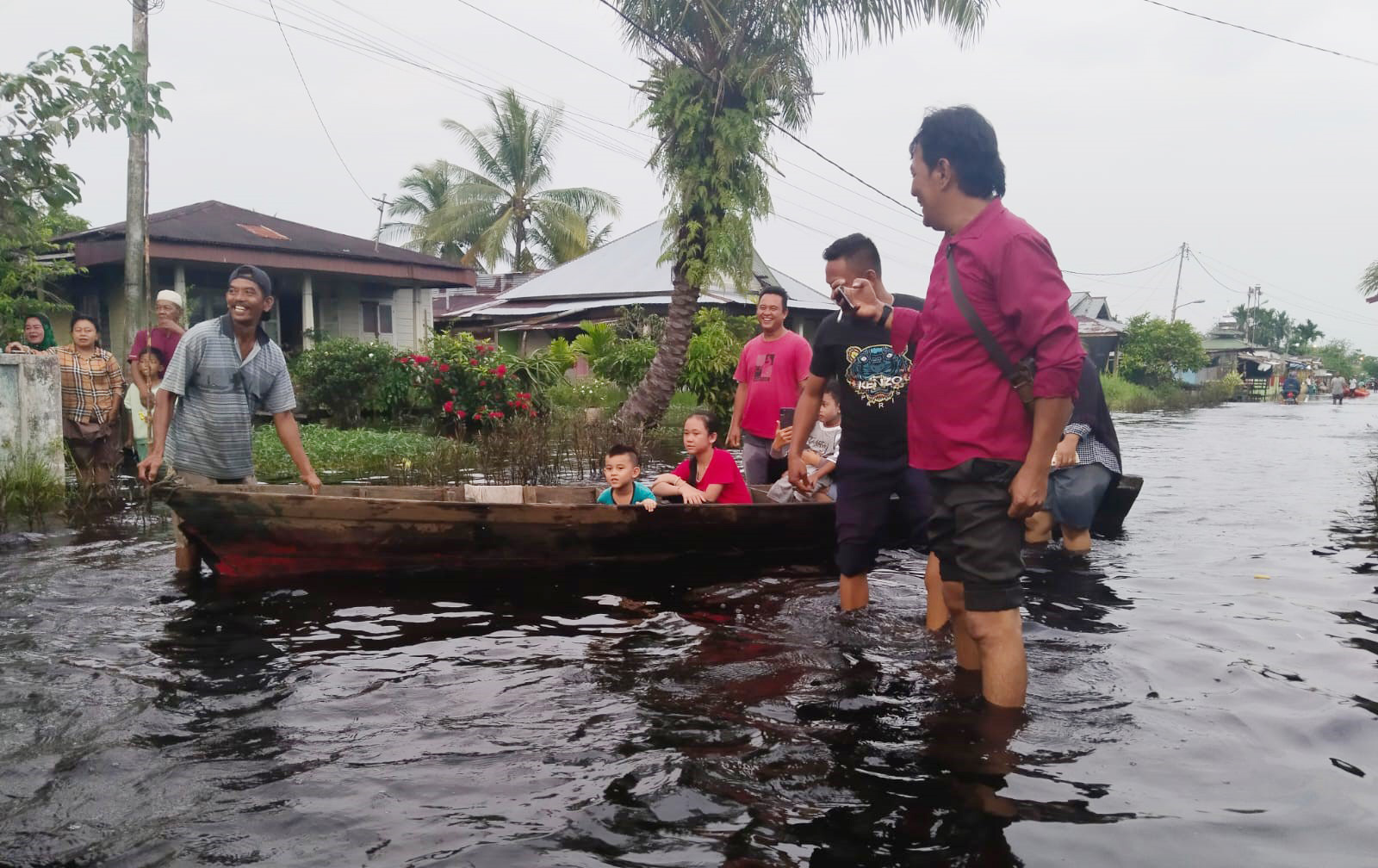 Warga menggunakan sampan saat melewati jalan yang digenangi air di Jalan Siak, Kelurahan Bagan Timur, Bangko, Bagansiapiapi, Rokan Hilir, Selasa (8/10/2024).