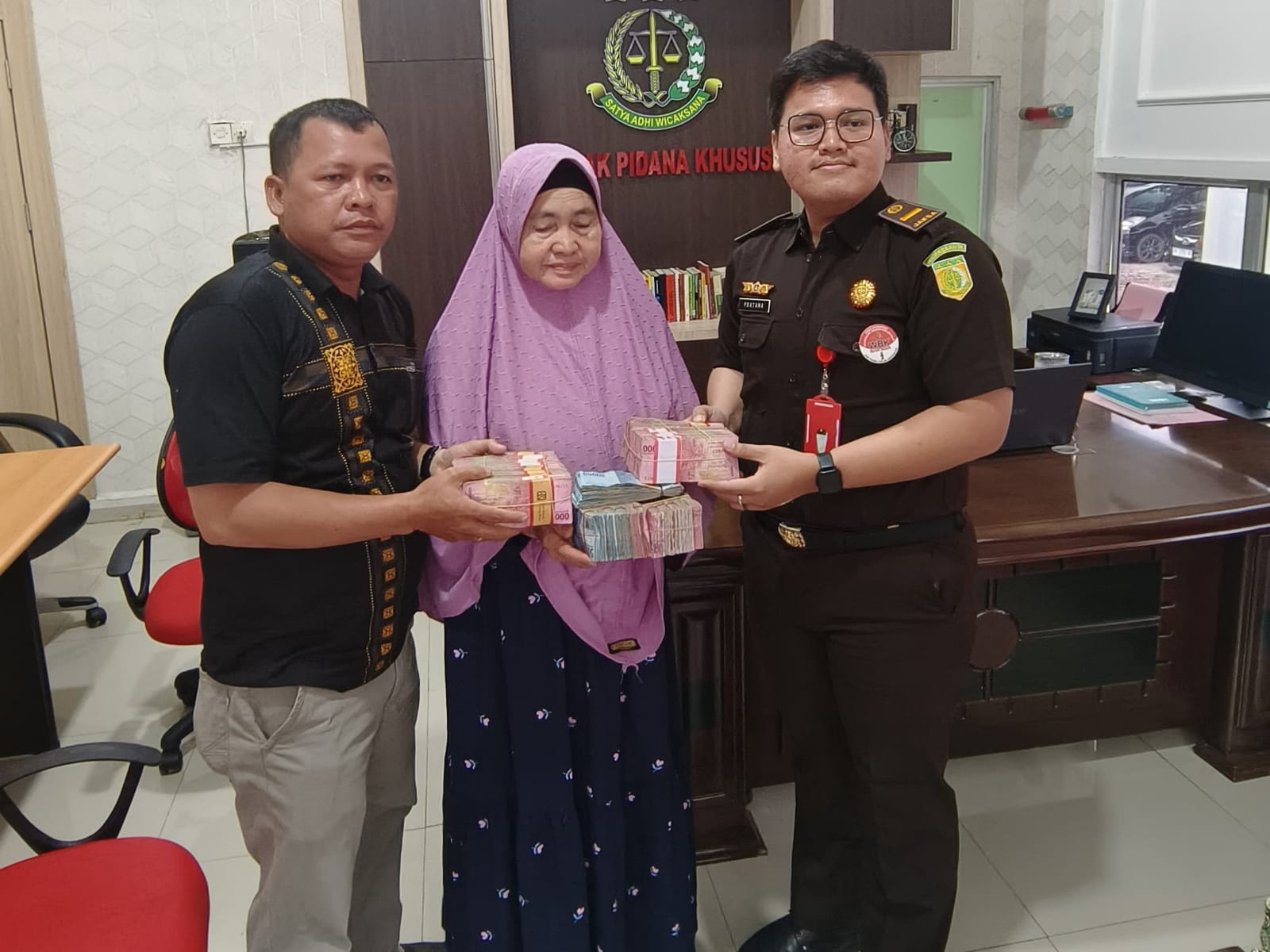 Keluarga terpidana Syahfrizal saat pengembalian uang kerugian negara kepada Kejari Rohil di Bagansiapiapi, Kamis (10/10/2024).