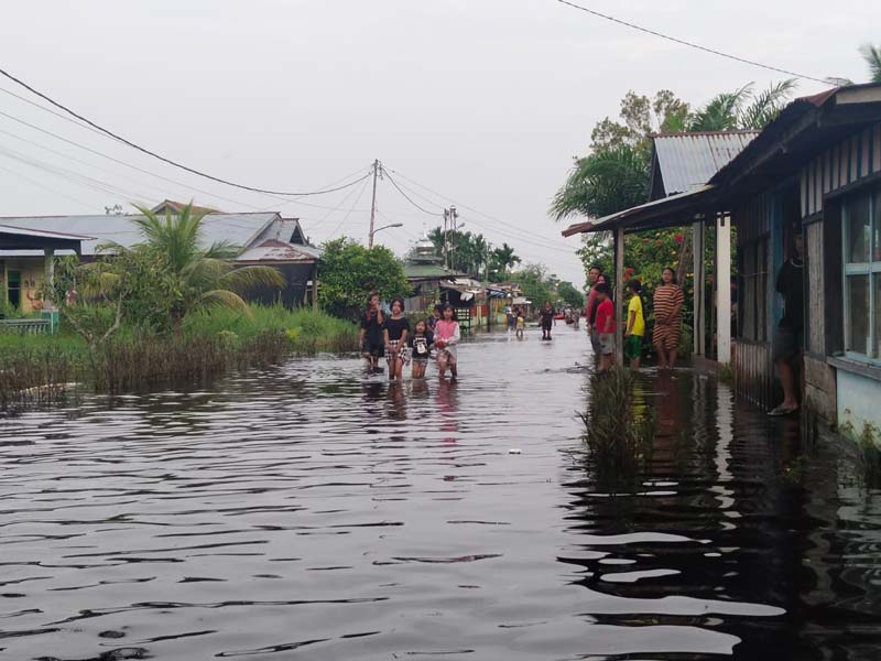 Sejumlah warga melintasi jalan yang digenangi banjir di Jalan Siak, Kelurahan Bagan Timur, Bangko, Rokan Hilir, Kamis (10/10/2024).